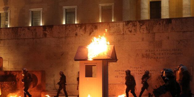 Riot police walk among flames by petrol bombs as a guard post of the Tomb of the Unknown Soldier burns during clashes outside the parliament building as Greek lawmakers vote on the latest round of austerity Greece has agreed with its lenders, in Athens, Greece, May 18, 2017. REUTERS/Costas Baltas