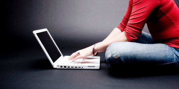 '* Young attractive woman in red tshirt and blue jeans on professional laptop computer, on black backdrop'