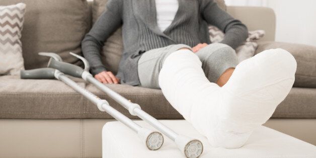 Close-up Of Woman With Plastered Leg Sitting On Couch At Home