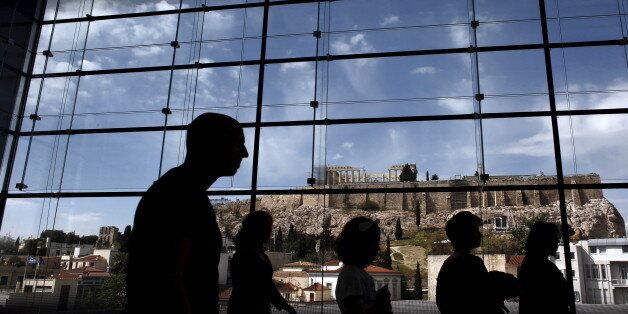 Tourists are silhouetted as they walk inside the Acropolis Museum with the temple of Parthenon on the background in Athens, April 25, 2015. Greece's governors and other local officials agreed on Saturday to lend cash to the near-bankrupt central government after Prime Minister Alexis Tsipras assured them the measure would last for only a short period of time. REUTERS/Kostas Tsironis