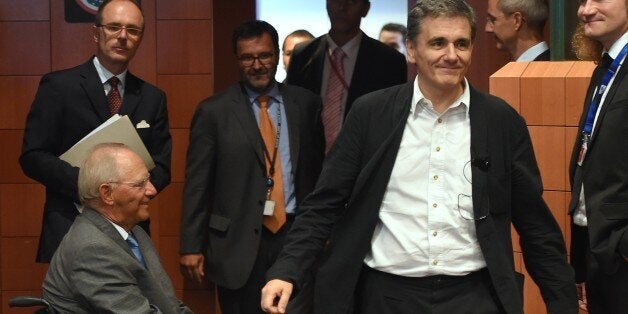 German Finance Minister Wolfgang Schauble (L seated) and Greece's Finance Minister Euclid Tsakalotos (R) arrive to attend an extraordinary Eurogroup meeting on Greece at the European Council in Brussels, on August 14, 2015.Eurozone finance ministers are scheduled to meet to go over a new bailout programme in return for reforms by Greece, but some of the creditors feel Athens' pledges are not precise enough. AFP PHOTO/Emmanuel Dunand (Photo credit should read EMMANUEL DUNAND/AFP/Getty Images)