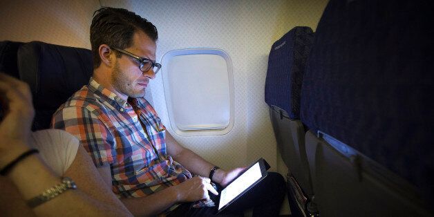 A passenger uses a wireless tablet on an American Airlines airplane, which is equipped with Gogo Inflight Internet service, enroute from Miami to New York December 10, 2013. Wi-Fi in the sky is taking off, promising much better connections for travelers and a bonanza for the companies that sell the systems. With satellite-based Wi-Fi, Internet speeds on jetliners are getting lightning fast. And airlines are finding that travelers expect connections in the air to rival those on the ground - and at lower cost. Picture taken December 10, 2013. To match Analysis AIRLINES-WIFI/ REUTERS/Carlo Allegri (UNITED STATES - Tags: TRANSPORT ENTERTAINMENT BUSINESS SCIENCE TECHNOLOGY)