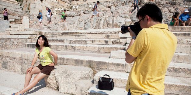 A Chinese tourist photographs his girlfriend. Tourists and visitors climbing up the marble stept towards the Acropolis of Athens. The main buildings on the Acropolis were built by Pericles in the fifth century BC as a monument to the cultural and political achievements of the inhabitants of Athens. The term acropolis means upper city and many of the city states of ancient Greece are built around an acropolis where the inhabitants can go as a place of refuge in times of invasion. It's for this reason that the most sacred buildings are usually on the acropolis. It's the safest most secure place in town. As little as 150 years ago there were still dwellings on the Acropolis of Athens. Athens is the capital and largest city of Greece. It dominates the Attica periphery and is one of the world's oldest cities, as its recorded history spans around 3,400 years. Classical (Photo by In Pictures Ltd./Corbis via Getty Images)