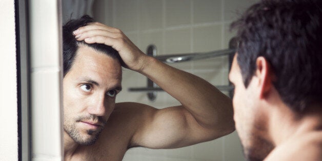 Man checking hair in mirror.