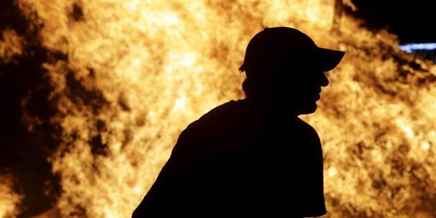 A man watches a bonfire during the traditional San Juan's (Saint John) night in Paredes, northern Spain early June 24, 2015. Fires are lit throughout Spain on the eve of Saint John where people burn objects they no longer want and make wishes as they jump through the flames. REUTERS/Miguel Vidal