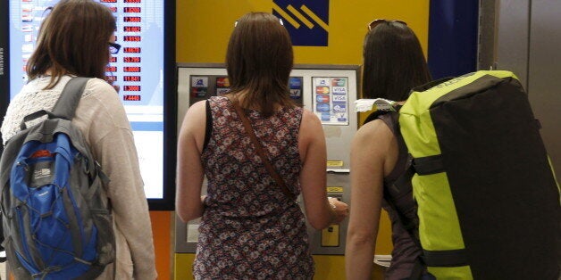 Tourists line up at an ATM at Athens international airport upon their arrival in Greece June 29, 2015. Greece closed its banks and imposed capital controls on Sunday to check the growing strains on its crippled financial system, bringing the prospect of being forced out of the euro into plain sight. REUTERS/Marko Djurica