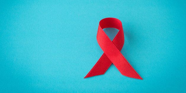 red aids ribbon on blue background. symbol world aids day.