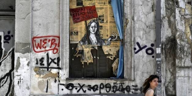 A woman walks past a political graffiti in central Athens by artist Bleeps reading' Bid! a few items left on sale' on May 4, 2017 one day after Greece and its creditors closed a troubled chapter on fiscal reforms with a preliminary deal on pension and tax cuts, offering hope for a debt relief agreement later this month Greece and its creditors on May 3rd closed a troubled chapter on fiscal reforms with a preliminary deal on pension and tax cuts, offering hope for a debt relief agreement later this month. The nation's debt in 2016 stood at nearly 315 billion euros or 179 percent of annual economic output, up from 177.4 percent in 2015. / AFP PHOTO / LOUISA GOULIAMAKI (Photo credit should read LOUISA GOULIAMAKI/AFP/Getty Images)