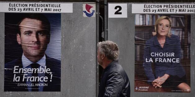 A pedestrian walks past posters of French presidential election candidate for the En Marche ! movement Emmanuel Macron (L) and French presidential election candidate for the far-right Front National (FN) party Marine Le Pen, in Paris, on April 28, 2017. / AFP PHOTO / Philippe LOPEZ (Photo credit should read PHILIPPE LOPEZ/AFP/Getty Images)