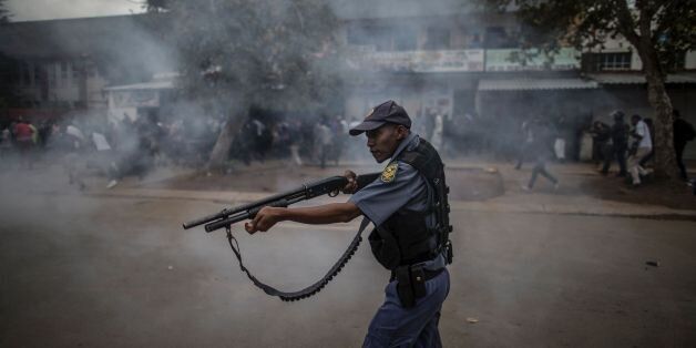 TOPSHOT - A South African police forces aims his rifle during a stand off between members of the Somali community and anti immigrant demonstrators in the Marabastad neighbourhood in Pretoria on February 24, 2017.South African police fired rubber bullets, tear gas and stun grenades to break up violent clashes between local protesters and migrants in Pretoria on February 24, 2017 at an anti-immigration march. Attacks against foreigners in the country have erupted regularly in recent years, fuelled by high unemployment and dire poverty. / AFP / MARCO LONGARI (Photo credit should read MARCO LONGARI/AFP/Getty Images)