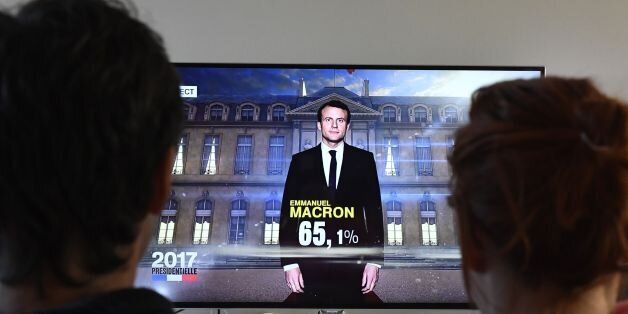 A couple watch a TV screen displaying French President elected Emmanuel Macron with an estimated score of more than 65 precent, on May 7, 2017 in Hede-Bazouges, western France.Pro-European centrist Emmanuel Macron won France's landmark presidential election, first estimates showed today, heading off a fierce challenge from the far-right in a pivotal vote for the future of the divided country and Europe. / AFP PHOTO / DAMIEN MEYER (Photo credit should read DAMIEN MEYER/AFP/Getty Images)