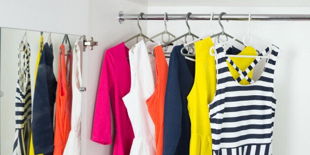 a series of bright modern fashion women's dresses on hangers in a white cupboard for summer and spring