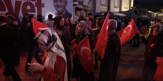 Residents carry Turkish national flags outside of the AKP party headquarters as they react to the outcome...