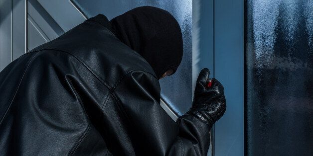 burgler with screwdriver trying to open a front door