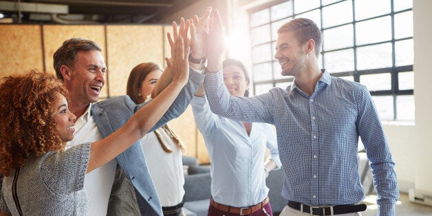 Cropped shot of a group of businesspeople high fiving in the office