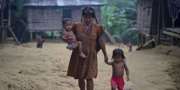 An Embera indigenous woman walks with her children in Puesto Indio, a rural village in Alto Baudo, department of Choco, western Colombia, on January 25, 2017.Despite the peace deal signed by the Colombian government and the FARC rebels, a turf war for control over drug trafficking routes in the isolated department of Choco continues to rage between the smaller ELN guerrilla group and the Autodefensas Gaitanistas de Colombia, a criminal gang that emerged after the paramilitary demobilization a decade ago. / AFP / LUIS ROBAYO / TO GO WITH AFP STORY BY ALINA DIESTE (Photo credit should read LUIS ROBAYO/AFP/Getty Images)