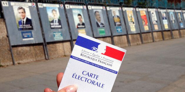 PARIS, FRANCE - APRIL 20: In this photo illustration, a French voter registration card is seen in front of official campaign posters for all eleven candidates for the 2017 French presidential elections posted outside a polling station on April 20, 2017 in Paris, France. French 2017 presidential election which will take place on April 23 and May 07, 2017. (Photo Illustration by Chesnot/Getty Images)