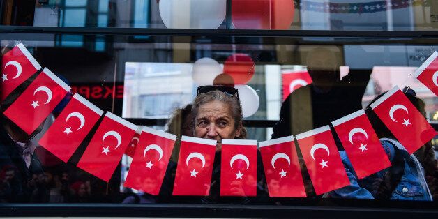TOPSHOT - A woman looks from a window as demonstrators shout during a protest against the result of the nationwide referendum that will hugely enhance the president Recep Erdogan powers at the Kadikoy district in Istanbul on April 23, 2017. Turkey's main opposition party launched a legal challenge at a top court on April 21 to last-minute changes to voting rules in the referendum that saw President Recep Tayyip Erdogan win expanded powers. / AFP PHOTO / YASIN AKGUL (Photo credit should read YASIN AKGUL/AFP/Getty Images)