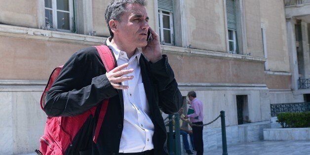 Greek Finance Minister Euclid Tsakalotos talks on his mobile phone outside the Greek parliament in Athens on July 22, 2015. Prime Minister Alexis Tsipras faced a new test of his authority in parliament on July 22, where MPs were to vote on a second batch of reforms to help unlock a bailout for Greece's stricken economy. The embattled premier last week faced a revolt by a fifth of the lawmakers in his radical-left Syriza party over changes to taxes, pensions and labour rules demanded by EU-IMF cr