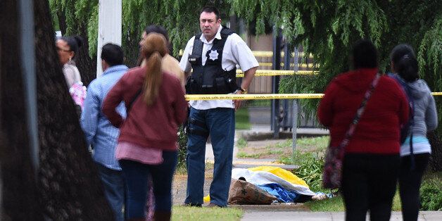 A Fresno police detective stands over the body of one of the three shooting victims as office workers are evacuated on Fulton Street, just north of Nevada Street, on Tuesday, April 18, 2017. (John Walker/Fresno Bee/TNS via Getty Images)