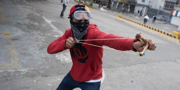 CARACAS, VENEZUELA-APRIL 22: A Venezuelan opposition activist use a sling shot as they clash with the police during a march against the government of President NIcolas Maduro, in Caracas, on April 22, 2017. Venezuelans gathered Saturday for 'silent marches' against President Nicolas Maduro, a test of his government's tolerance for peaceful protests after three weeks of violent unrest that has left 20 people dead. (Photo by Carlos Becerra/Anadolu Agency/Getty Images)