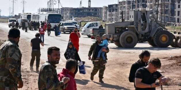 Syrians who were injured in a car bomb blast on April 15 while they were waiting at a transit point during their evacuation from the sieged government-held towns of Kufraya and Fuaa in a deal made between the government and the rebels, are assisted by government forces and members of the Syrian Arab Red Crescent as they arrive in the northern city of Aleppo to receive medical treatment on April 19, 2017. The evacuation of civilians and fighters from besieged Syrian towns resumed after the weekend bombing that killed 126 people, 68 of them children, an AFP correspondent reported. / AFP PHOTO / George OURFALIAN (Photo credit should read GEORGE OURFALIAN/AFP/Getty Images)