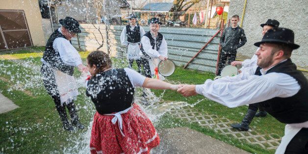 IAROVCE, SLOVAKIA - MARCH 28: Men seen throwing buckets of water on a woman as part of Easter celebrations on March 28, 2016 in iarovce, Slovakia. Hungarian men and boys from the local NapraforgÃ³ folk dance group dressed in their traditional costumes from the village of iarovce take great delight in pouring buckets of water over the local girls and women as part of their Easter celebration. However this tradition is at the brink of extinction, with only a few continuing this beautiful yet str