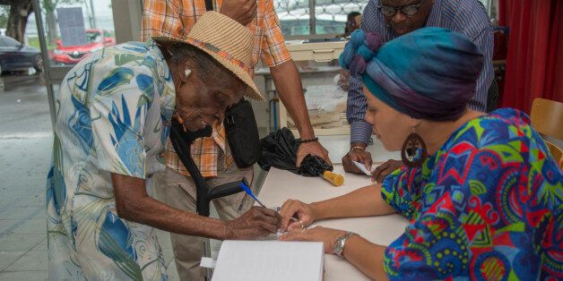 An elderly woman signs the register after casting her ballot as part of the first round of the French presidential elections, on April 22, 2017 in Pointe-Ã -Pitre, on the French Caribbean island of Guadeloupe. / AFP PHOTO / Helene Valenzuela (Photo credit should read HELENE VALENZUELA/AFP/Getty Images)