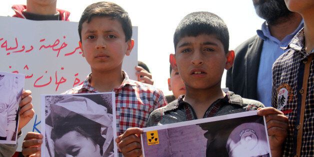 Syrian residents of Khan Sheikhun hold placards and pictures on April 7, 2017 during a protest condemning a suspected chemical weapons attack on their town that killed at least 86 people, among them 30 children, and left hundreds suffering symptoms including convulsions, vomiting or foaming at the mouth. In the Syrian town of Khan Sheikhun, site of an alleged chemical weapons attack, residents still mourning their dead welcomed US strikes as a way to pressure Damascus. The attack ordered by President Donald Trump was the first direct US military action against Syria's government since the conflict began six years ago. / AFP PHOTO / Omar haj kadour (Photo credit should read OMAR HAJ KADOUR/AFP/Getty Images)