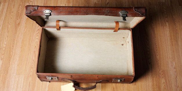 Empty old open leather suitcase with old luggage label, wooden floor, and copy space