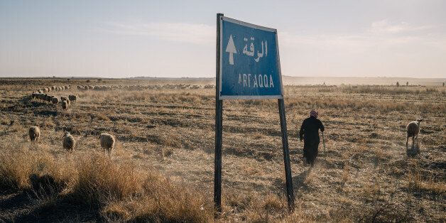 AIN ISSA, SYRIA, NOV 22: A shepherd passes by a sign indicating the direction to Raqqa city. (Photo by Alice Martins for The Washington Post via Getty Images)