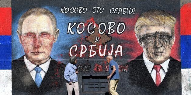 People walk past a wall depicting Russian President Vladimir Putin (L) and US President Donald Trump and with a message in cyrillic letters reading 'Kosovo is Serbia' in Belgrade on April 2, 2017.Serbians head to the polls to elect a new president, with strongman Aleksandar Vucic hoping to tighten his grip on power amid opposition accusations he is shifting the country to authoritarian rule. / AFP PHOTO / ANDREJ ISAKOVIC (Photo credit should read ANDREJ ISAKOVIC/AFP/Getty Images)