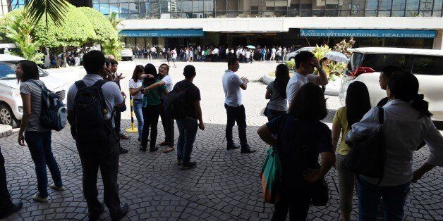 Office workers stand on the grounds of an office building in the financial district of Makati in Manila on April 8, 2017, after a 5.7 magnitude earthquake.A magnitude 5.7 earthquake rocked the Philippines on April 8, the US Geological Survey said, sending people running out of buildings in the capital Manila. / AFP PHOTO / Ted ALJIBE (Photo credit should read TED ALJIBE/AFP/Getty Images)