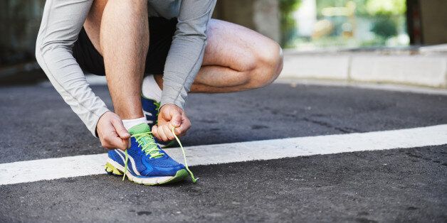 Cropped image of a young man tying his laces before a run