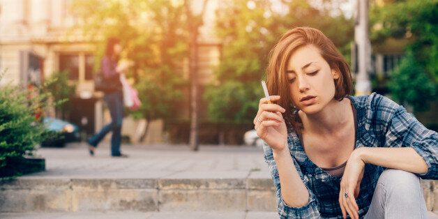 Sad teenage girl smoking outside - copyspace
