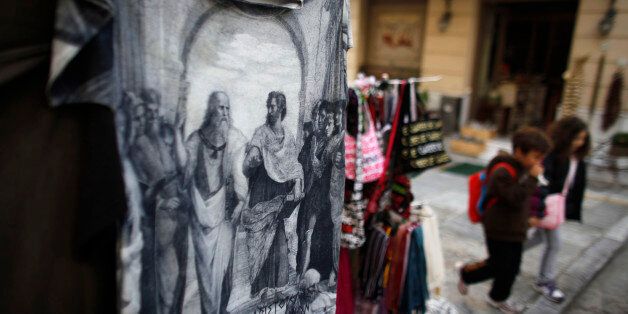 Children pass a souvenir shop displaying a t-shirt with illustrations of the ancient Greek philosophers, Plato and Aristotle, in the Plaka tourist district of Athens, Greece, on Friday, Nov. 4, 2011. Greek politicians are trying to map out a plan to put in place a new government to ratify last week's European Union bailout agreement as Prime Minister George Papandreou struggles to keep his majority in parliament. Photographer: Kostas Tsironis/Bloomberg via Getty Images