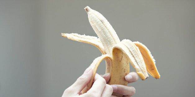 Human hands taking off skin of banana.