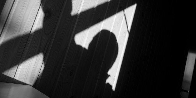 Shadow of a burglar (or murderer or rapist) while he enters through an open window. A closed and locked glass door (with doorhandle) can be seen in the background to the right. The image was shot around dusk.