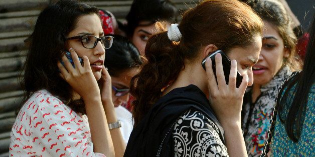 Pakistani office workers speak on their mobile phones on the street after an earthquake in Karachi on September 24, 2013. A powerful 7.8-magnitude earthquake hit southwestern Pakistan on, the US Geological Survey said, with tremors felt as far away as the Indian capital New Delhi. The area of the epicentre is sparsely populated, but the USGS issued a red alert for the quake, warning that heavy casualties were likely, based on past data. AFP PHOTO/ Rizwan TABASSUM (Photo credit should read RIZWAN TABASSUM/AFP/Getty Images)
