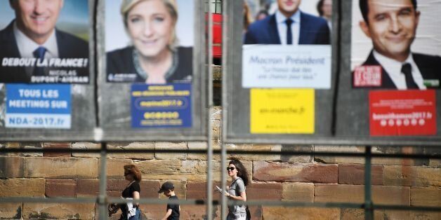 People walk past campaign posters of candidates for the French presidential election on April 10, 2017 in Strasbourg, eastern France.The first round of the French presidential election will take place on April 23. / AFP PHOTO / FREDERICK FLORIN (Photo credit should read FREDERICK FLORIN/AFP/Getty Images)