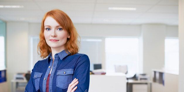 Young businesswoman crossing arms in an office