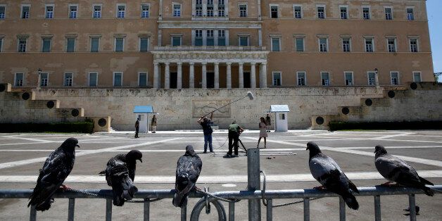 Pigeons perch on a police fence as a television crew films in front of the Greek parliament at an empty Syntagma (Constitution) square in central Athens during a visit by German Finance Minister Wolfgang Schaeuble July 18, 2013. Greek police have banned protests and traffic in downtown Athens on Thursday during a visit by Schaeuble, whom many accuse of forcing painful cuts on Greece in return for the multi-billion euro bailouts keeping it afloat. REUTERS/Yannis Behrakis (GREECE - Tags: POLITICS