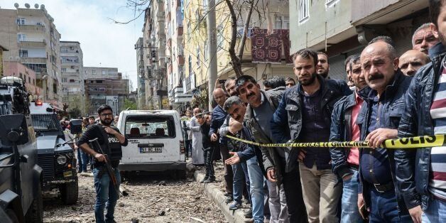 People gather behind a cordon near police officers next to the site of an explosion at the police headquarters in Diyarbakir, southeastern Turkey, on April 11, 2017.The explosion which shook police headquarters in Diyarbakir on the morning of April 11 was an accident which occurred during repair work. According to Turkey's Interior Minister, no external forces had been involved in the incident in the restive majority Kurdish city which happened during repair work on armoured vehicles at police headquarters. He said one person was seriously hurt while another was trapped under rubble. / AFP PHOTO / ILYAS AKENGIN (Photo credit should read ILYAS AKENGIN/AFP/Getty Images)