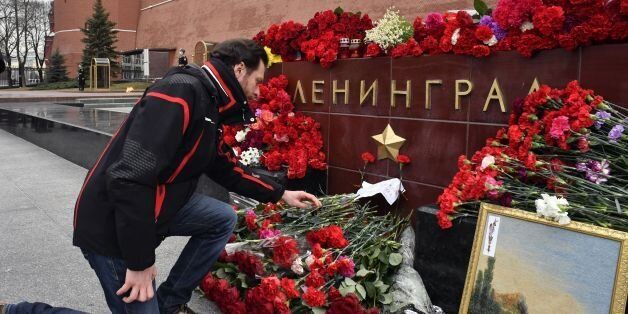 A man lays flowers in honour of the victims of the April 3 blast in the Saint Petersburg metro at a memorial stone reading Leningrad by the Kremlin wall in central Moscow on April 4, 2017.The death toll from an bombing on a metro train in Russia's second city Saint Petersburg rose to 14 Tuesday, as Kyrgyzstan said a suicide bomber from the Central Asian country had staged the attack. / AFP PHOTO / Yuri KADOBNOV (Photo credit should read YURI KADOBNOV/AFP/Getty Images)