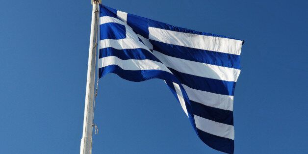 The blue and white official flag of Greece against blue sky.