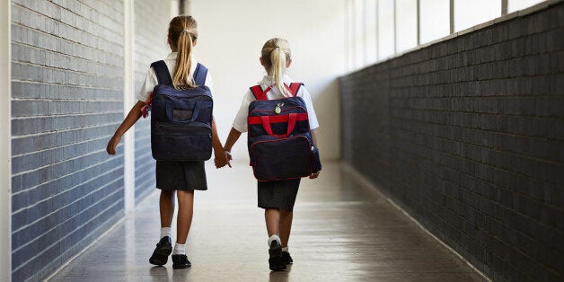 Schoolgirls walking hand in hand at school isle