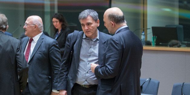 Euclid Tsakalotos, Greece's finance minister, center, speaks with Pierre Moscovici, economic commissioner for the European Union (EU), right, ahead of a Eurogroup meeting of finance ministers in Brussels, Belgium, on Monday, March 20, 2017. Wolfgang Schaeuble, Germany's finance minister, said to reporters ahead of the meeting of euro-area finance ministers Well get a report on Greece, but the mission isnt completed,. Photographer: Jasper Juinen/Bloomberg via Getty Images