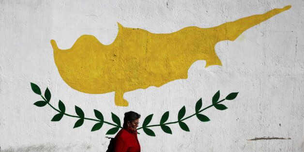 A woman walks in front of Cypriot flag painted on a wall in capital Nicosia, Cyprus February 22, 2017. REUTERS/Yiannis Kourtoglou