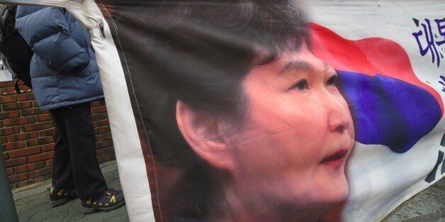 Supporter of South Korea's impeached ex-president Park Geun-Hye stand in front of a wall displayed with rose and pictures of Park outside the former leader's residence in Seoul on March 27, 2017.South Korean prosecutors sought an arrest warrant on March 27 for ousted president Park Geun-Hye, they said, days after questioning her over the corruption and abuse of power scandal that brought her down. / AFP PHOTO / JUNG Yeon-Je (Photo credit should read JUNG YEON-JE/AFP/Getty Images)