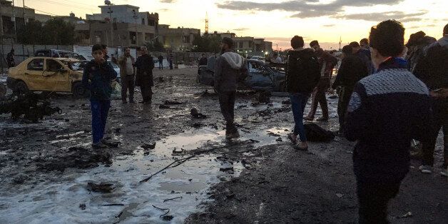 TOPSHOT - A picture taken with a mobile phone on February 16, 2017 shows locals looking through debris at the scene of a blast by a massive car bomb, which killed dozens in a used car market in southern Baghdad.The Amaq propaganda agency linked to the Islamic State group (IS), which has claimed nearly all such attacks recently, reported the blast and described it as targeting 'a gathering of Shiites'. / AFP / Ahmad MOUSA (Photo credit should read AHMAD MOUSA/AFP/Getty Images)